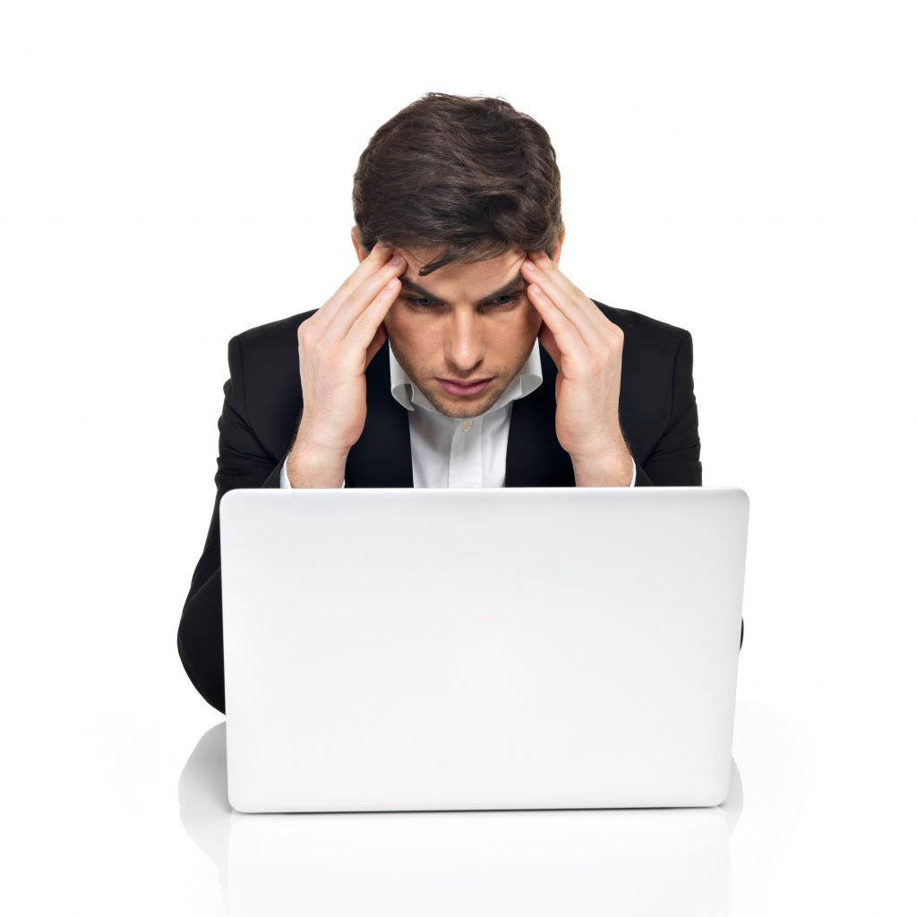 A worried man in a coat looking at his laptop